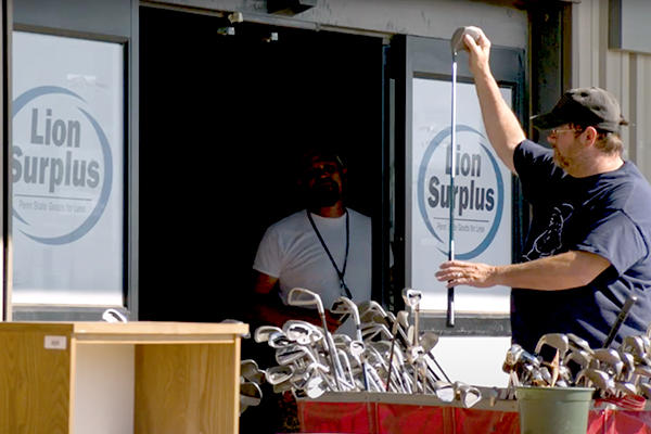 Employees examining golf clubs outside the Lion Surplus store